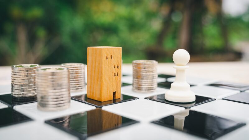 Wooden peg figures and stacks of coins on a chessboard