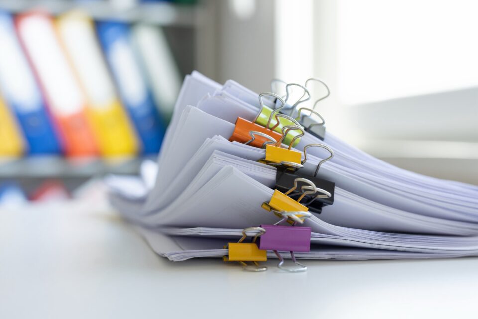 Stack of colorful binders and folders clipped together with binder clips