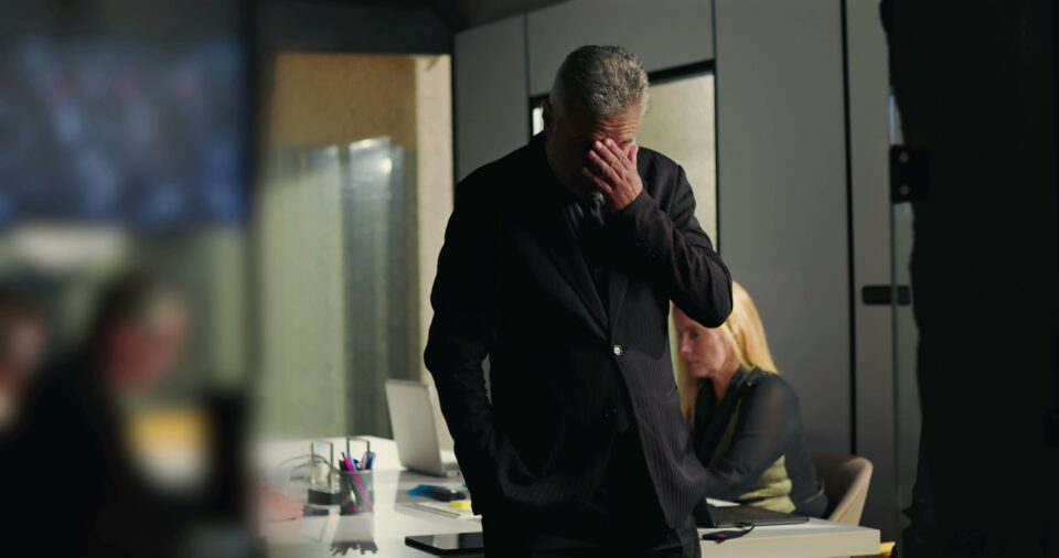Frustrated businessman with his hand over his face in an office at night